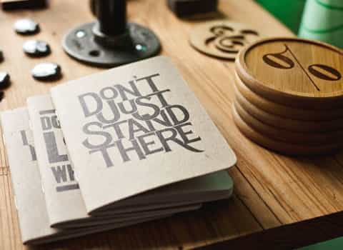 Wooden items, a stack of notebooks folded on a table.