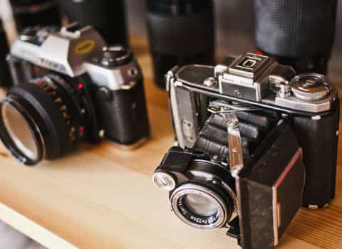 Two very old cameras on a shelf.