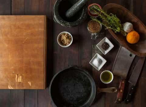 Board for slicing, frying pan, two knives on a wood table.